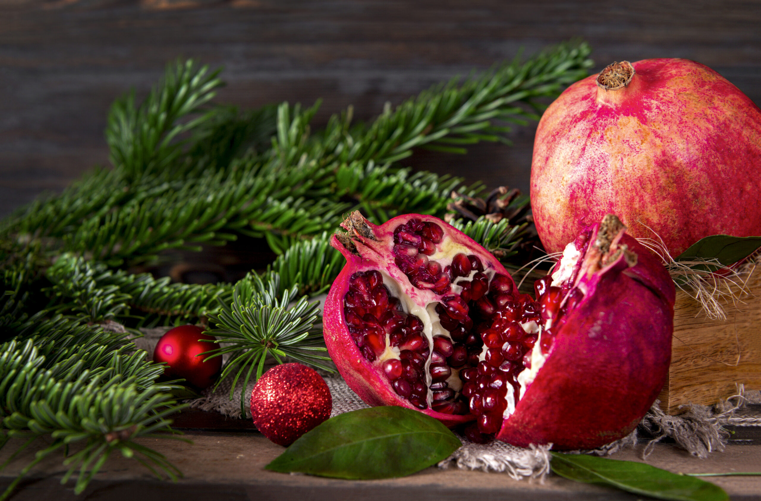 pomegranate sliced open on pine branches