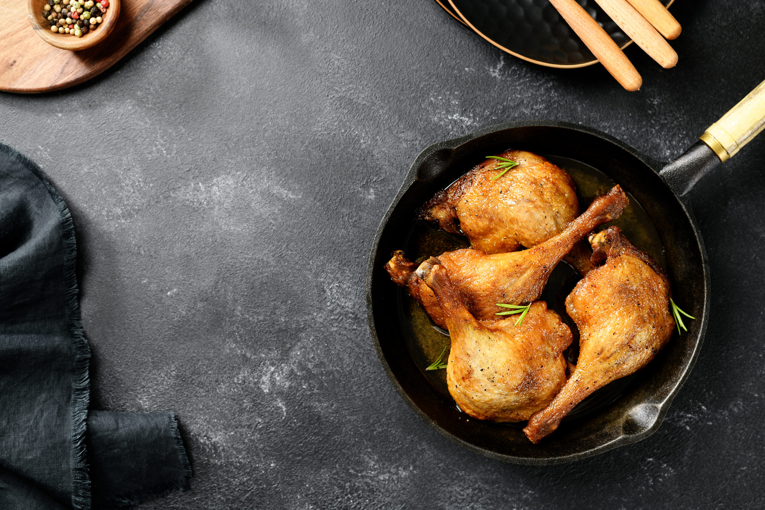 Freshly roasted duck legs confit in pan, top view, black background