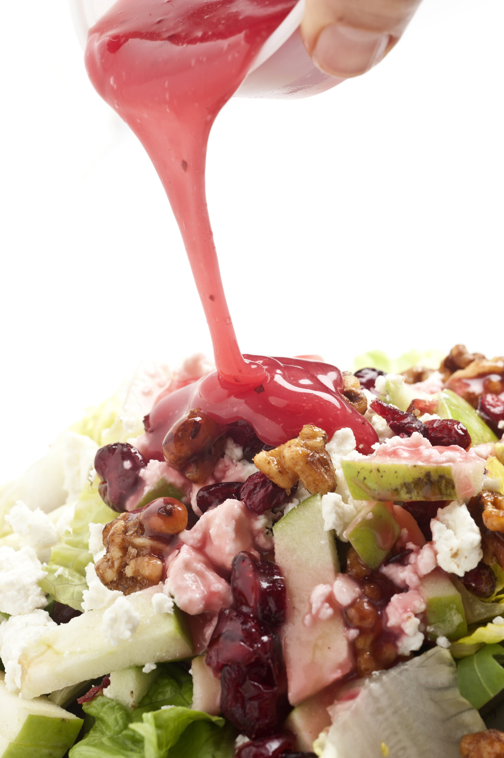 pouring pomegranate dressing over salad